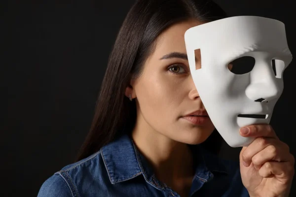 Multiple personality concept. Woman with mask on black background